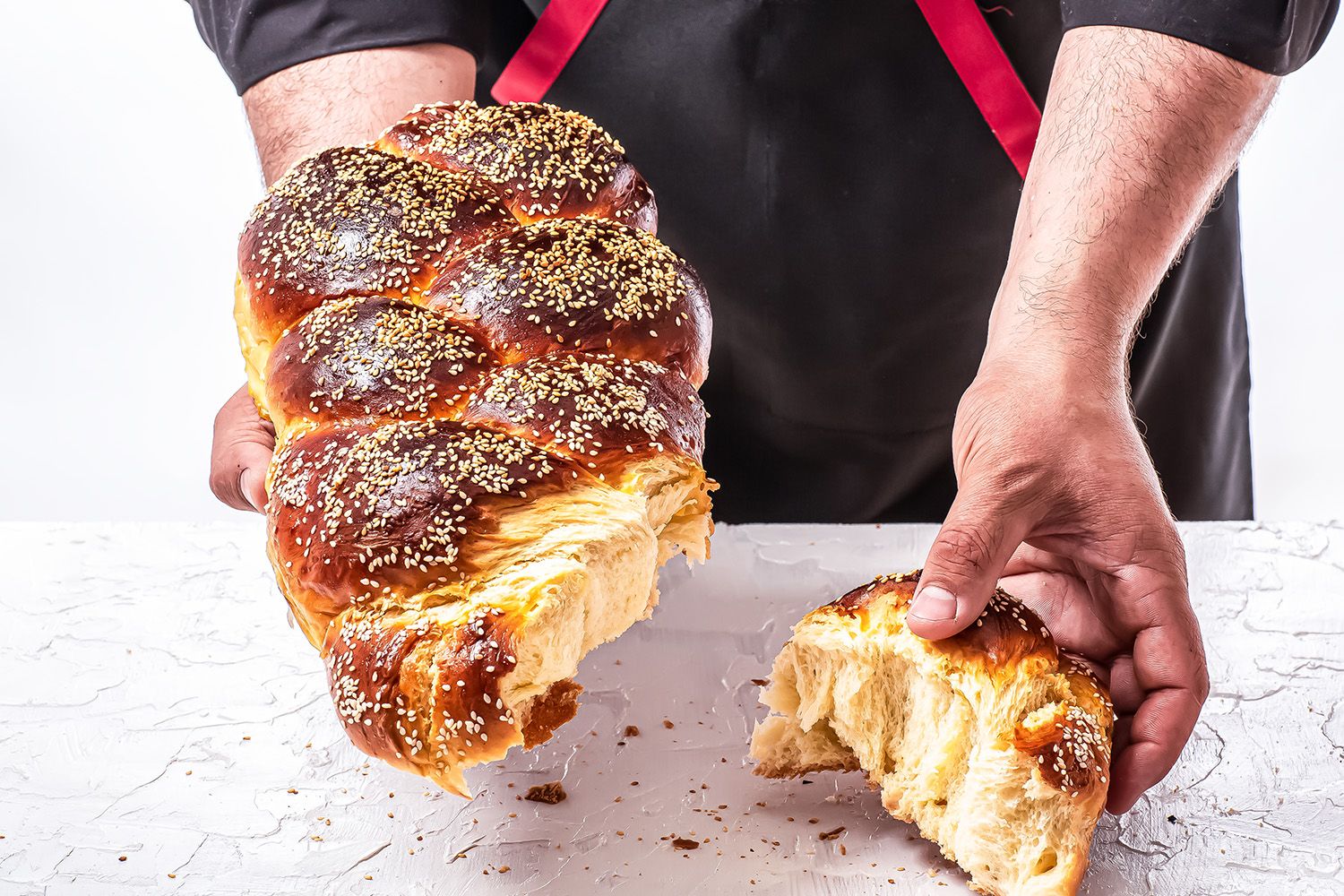 a baker holding a piece of challah bread for sandwiches