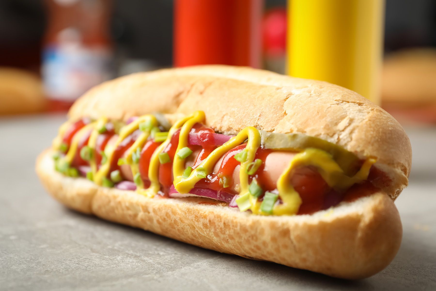 A hot dog sandwich served on a split roll with mustard, onions and ketchup