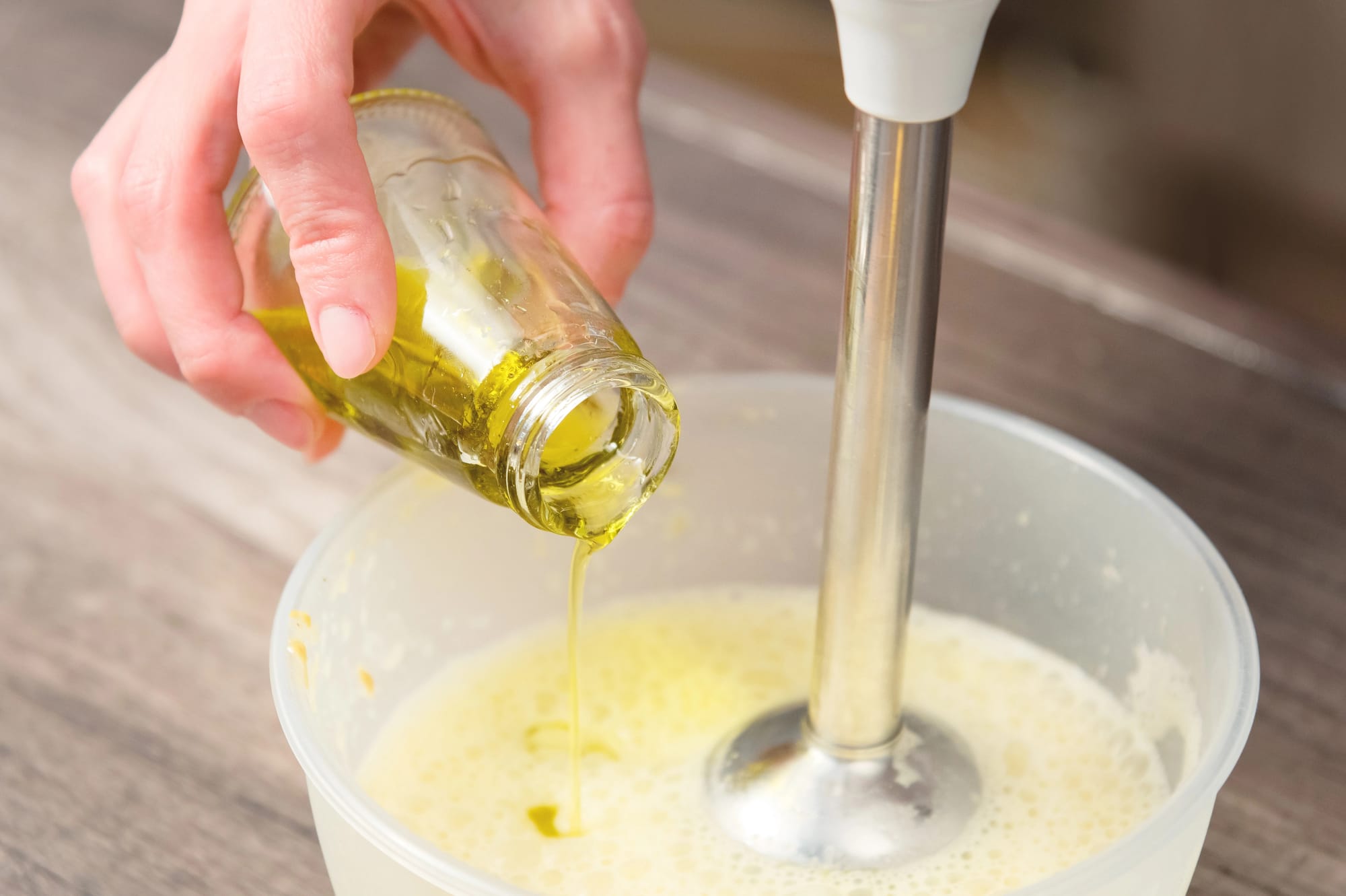 adding olive oil to homemade mayonnaise