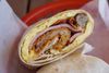 a meat breakfast burrito with eggs, ham, sausage, bacon cheese, and a hashbrown