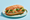 A shredded-chicken bánh mì on a green plate, the baguette split to show pulled chicken with shredded cabbage, pickled carrot, cucumber slices and coriander.