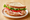 A turkey sandwich on a white plate, two slices of seeded bread around ruffled sliced turkey breast with tomato, green leaf lettuce and mayonnaise.