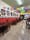 Dining room with papel picado bunting, framed art on a red-and-white wall, wooden tables and a deli counter at the back