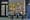 Maison Alyzee storefront: black-framed glass front, gold window lettering, four woven bistro chairs and two cafe tables outside