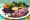 Plate of rice, black beans, fried pork, pickled red onions, plantains and greens on a floral oilcloth