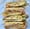 Four halves of pressed panini stacked on white butcher paper, ham, roast pork, pickles, tomato and cheese showing