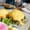 Eggs Benedict under hollandaise on toast with greens and tomato, a knife and fork poised above the plate