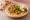 Abu Hassan (Ali Karavan): an illustration of hummus, chickpeas, tahini, olive oil and more on pita.