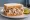 Alabama White Sauce Chicken Sandwich: an illustration of chicken, mayonnaise, pepper and pickle on white bread.