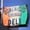 Weathered hanging sign in Italian flag colours reading Domenico's Italian Deli, with a sub sandwich drawing, against blue sky