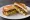 Avocado and Bacon: an illustration of bacon and avocado on white bread.