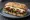Bacon and Brie: an illustration of bacon, brie, cranberry sauce and arugula on ciabatta.