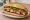 Bánh Mì Ba Chỉ: an illustration of pork belly, đồ chua, cilantro, cucumber and more on bánh mì baguette.