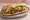 Bánh Mì Bò Xào: an illustration of beef, onion, mayonnaise, đồ chua and more on bánh mì baguette.