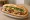 Bánh Mì Cánh Gà Nướng: an illustration of chicken, mayonnaise, đồ chua, cucumber and more on bánh mì baguette.