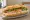 Bánh Mì Chả Gà: an illustration of chicken, đồ chua, cucumber, cilantro and more on bánh mì baguette.