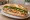 Bánh Mì Chay Rằm: an illustration of mock meat, đồ chua, cucumber, cilantro and more on bánh mì baguette.