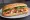 Bánh Mì Gà Chiên: an illustration of chicken, đồ chua, cucumber, cilantro and more on bánh mì baguette.