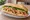 Bánh Mì Gà Nướng Sả: an illustration of chicken, lemongrass, đồ chua, cucumber and more on bánh mì baguette.