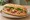 Bánh Mì Gà Quay: an illustration of chicken, đồ chua, cucumber, cilantro and more on bánh mì baguette.