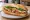 Bánh Mì Gà Xào Sả Ớt: an illustration of chicken, lemongrass, pepper, đồ chua and more on bánh mì baguette.