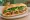 Bánh Mì Heo Chay: an illustration of mayonnaise, đồ chua, cucumber and cilantro on bánh mì baguette.