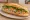 Bánh Mì Mắm Chưng: an illustration of pork, egg, đồ chua, cucumber and more on bánh mì baguette.