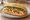 Bánh Mì Mực: an illustration of squid, đồ chua, cucumber and cilantro on bánh mì baguette.
