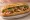 Bánh Mì Mực Nướng: an illustration of squid, đồ chua, cucumber and cilantro on bánh mì baguette.