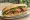 Bánh Mì Nem Lụi: an illustration of pork, lemongrass, đồ chua, cucumber and more on bánh mì baguette.