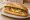 Bánh Mì Ốp La Bơ: an illustration of egg, butter, đồ chua, cucumber and more on bánh mì baguette.