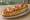 Bánh Mì Pizza: an illustration of pork, tomato, ketchup and cheese on bánh mì baguette.