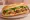 Bánh Mì Sườn Nướng: an illustration of pork, lemongrass, đồ chua, cucumber and more on bánh mì baguette.