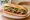 Bánh Mì Thịt Nướng Mật Ong: an illustration of pork, honey, đồ chua, cucumber and more on bánh mì baguette.