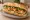 Bánh Mì Tôm: an illustration of shrimp, đồ chua, cucumber and cilantro on bánh mì baguette.