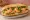 Bánh Mì Tôm Tempura: an illustration of shrimp, mayonnaise, đồ chua, cucumber and more on bánh mì baguette.