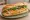 Bánh Mì Trứng Chiên: an illustration of egg, đồ chua, cucumber and cilantro on bánh mì baguette.