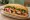 Bánh Mì Đùi Gà Nướng: an illustration of chicken, đồ chua, cucumber and cilantro on bánh mì baguette.