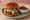 Birria Burger: an illustration of queso oaxaca on burger bun.