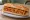 Bocadillo de Empanada: an illustration of pork, tuna, onion, tomato and more on baguette.