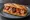 Bocadillo de Fabada: an illustration of pork, chorizo, morcilla, beans and more on baguette.