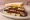 Brisket Sandwich (Texas): an illustration of beef, pickle and onion on white bread.