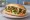 Broodje Falafel: an illustration of chickpeas, tahini, lettuce, tomato and more on kaiser roll.