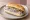 Broodje Haring: an illustration of herring, onion and pickle on kaiser roll.