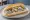 Broodje Hollandse Nieuwe: an illustration of herring, onion and pickle on kaiser roll.