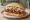 Broodje Jackfruit: an illustration of bbq sauce, coleslaw and onion on kaiser roll.
