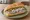 Broodje Maatjesharing: an illustration of herring, onion and pickle on kaiser roll.