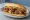 Broodje Moksi Meti: an illustration of chicken, pork and onion on kaiser roll.