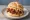 Broodje Pulled Pork: an illustration of pork, bbq sauce and coleslaw on kaiser roll.