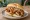 Broodje Saté met Pindasaus: an illustration of chicken, pork and onion on kaiser roll.